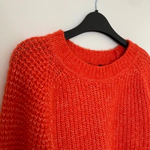 Orange stickad tröja - Säljer en härlig orange stickad tröja med rund hals och långa ärmar. Perfekt för att hålla sig varm under kyliga dagar. Tröjan har en mysig och avslappnad passform.