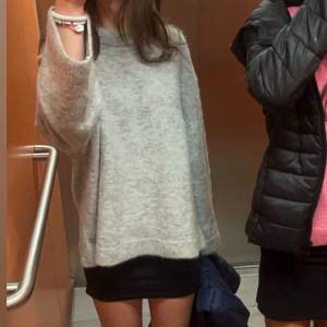 Mysig grå stickad tröja med långa ärmar och en avslappnad passform. Perfekt för kyligare dagar och enkel att matcha med olika outfits.