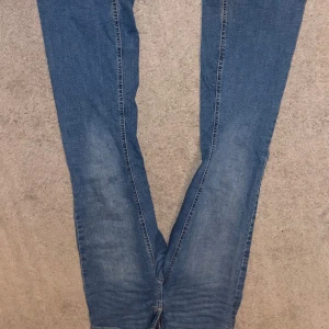 Blå jeans med knappar - Snygga blå jeans från ”Denim day”  med dragkedja och knappar i midjan. Byxorna har en klassisk design med fickor bak som stängs med knappar. Perfekta för en avslappnad stil. Enkla att styla, de är utsvängda/bootcut