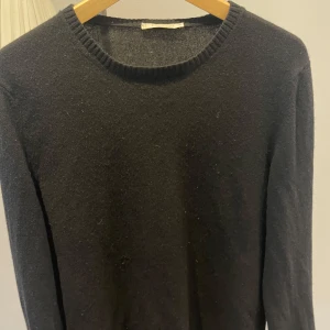 100% Kashmir tröja från BELLWOOD. NYPRIS 3519 kr, mycket bra skick. - Elegant svart kashmirtröja från Bellwood, perfekt för kyliga dagar. Tröjan har en klassisk rund hals och långa ärmar, vilket gör den både stilren och bekväm. Tillverkad i Italien av 100% kashmir för en lyxig känsla.