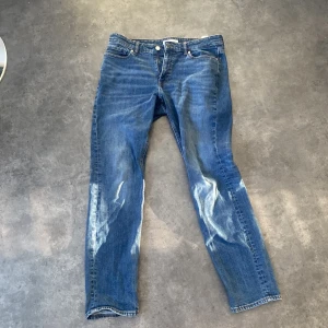 Blå jeans med läderdetalj (grisch jeans) - Snygga blå jeans med en slim passform och klassisk femficksdesign. De har en läderdetalj med text på baksidan av midjan. Perfekta för en avslappnad stil.