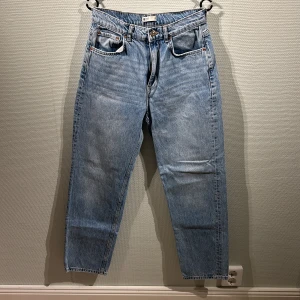 Blå jeans från Gina Tricot - Snygga blå jeans från Gina Tricot i en klassisk straight fit. De har en hög midja och är tillverkade i denim med en knapp och dragkedja framtill. Perfekta för en avslappnad stil.