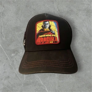 Svart keps med Dracula-motiv - Cool svart keps med ett färgglatt Dracula-motiv på framsidan. Kepsen har röd söm och ett nätmaterial på baksidan för ventilation. Märket Capslab syns på sidan. Perfekt för dig som gillar unika accessoarer!