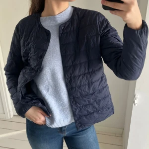 Blå quiltad jacka - Säljer en stilren marinblå quiltad jacka med knappar. Jackan har en normal passform och är perfekt för kyligare dagar. Den är lätt och smidig att bära, vilket gör den till ett mångsidigt plagg i garderoben.