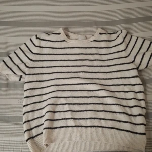 Randig tröja från H&M - Säljer en stilren randig tröja från H&M i svart och vit. Tröjan har korta ärmar och en rund halsringning, perfekt för en avslappnad look. Den är gjord i ett mjukt material som känns skönt mot huden. Och den passar för både barn och vuxna 