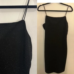 Barn - Svart glittrig klänning med smala axelband - BARNSTORLEK - Snygg svart klänning med glittrigt mönster och smala axelband. Perfekt för en speciell tillställning. Klänningen har en elegant och stilren design som framhäver figuren.