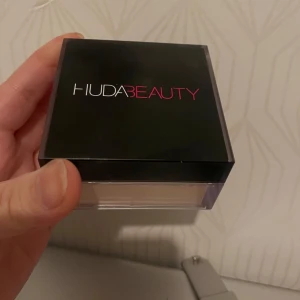 Hell ny Löspuder från Huda Beauty - Säljer ett hell ny och oanvänd  löspuder från Huda Beauty- Banana Bread.. Perfekt för att sätta sminket och ge en matt finish. Kommer i en fyrkantig behållare med svart lock och transparent botten.