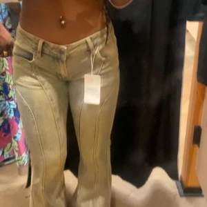 Beige bootcut jeans - Snygga beige bootcut jeans med låg midja och coola sömdetaljer. Perfekta för en avslappnad stil med en touch av retro. De har en klassisk femficksdesign och dragkedja.