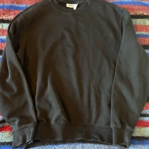 Svart sweatshirt från Weekday - Säljer en stilren svart sweatshirt från Weekday i storlek M. Tröjan har en klassisk rund hals och långa ärmar med ribbade muddar vid ärmslut och nederkant. Perfekt för en avslappnad look.