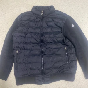 Svart pufferjacka med dragkedja - Snygg svart pufferjacka med dragkedja och ribbade muddar. Perfekt för kyliga dagar med sin quiltade design och långa ärmar. Jackan har en hög krage och två praktiska fickor med dragkedja.