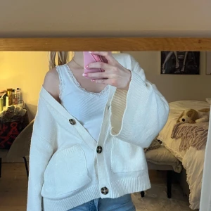 Vit ribbad linnetopp från Brandy Melville - Säljer en vit ribbad linnetopp från Brandy Melville med spetsdetaljer runt den v-ringade halsen. Perfekt för lager-på-lager eller att bära som den är. Superbekväm och stilren design. Onsize men XS-M! Mkt gott skick även fast den använts🤍