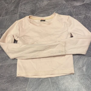 Ljus rosa långärmad croppad topp  - Säljer en stilren beige långärmad topp från Ginatricot. Den är croppad och passar perfekt för en trendig look. Perfekt för att matcha med höga jeans eller kjol.