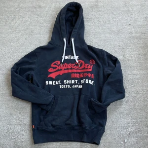 Fodrad Superdry hoodie - Tja! Säljer nu denna feta hoodie från Superdry! Den är mörkblå med ett snyggt rött tryck på. Hoodien är fodrad så den passar perfekt till dessa lite kyligare dagar!❄️ Nypris: 1499kr❌‼️ Vårat pris: 599kr✅ Skriv vid minsta fundering och pris kan alltid diskuteras!🤝🙌