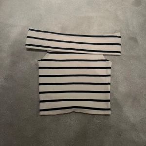 Randig offshoulder topp - Snygg randig offshoulder topp i svart och vit från GinaTricot. Toppen är i en liten kortare model. Används fåtal gången därför den inte passar mig längre.