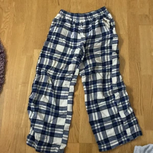 Pjammas byxa i blått och vitt - Säljer ett par bekväma byxor med rutigt mönster i blått och vitt. Byxorna har en loose passform och är perfekta för en avslappnad stil. De har elastisk midja för extra komfort.