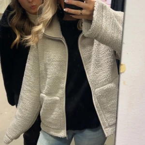 Beige teddyjacka med dragkedja - Mysig beige teddyjacka med dragkedja framtill. Perfekt för kyliga dagar med sin fluffiga och varma design. Jackan har långa ärmar och praktiska fickor på sidorna. En stilren och bekväm jacka för alla tillfällen. Helt oanvänd endast testad❤️