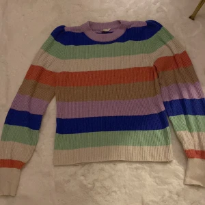 Randig stickad tröja från Cubus - Säljer en färgglad randig stickad tröja från Cubus. Tröjan har långa ärmar och är i flera färger som blå, grön, lila, beige och orange. Perfekt för att liva upp garderoben med lite färg!