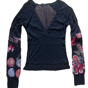 Svart långärmad topp med blommiga ärmar - Säljer en unik svart topp med djup v-ringning och långa mesh ärmar. Mesh genomskinlig rygg också. Passar XS-S 