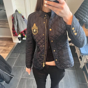 Svart quiltad jacka från Morris Lady - Säljer en snygg svart quiltad jacka från Morris Lady med guldknappar och ett elegant broderat emblem på bröstet. (Nypris 2 299kr) modellen säljs inte längre