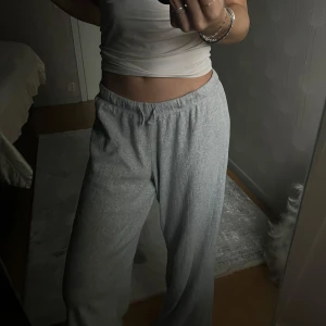 Grå low waist mjukisbyxor! - Säljer ett par grå low waist mjukisbyxor med loose passform. Byxorna har en elastisk midja för extra komfort och är perfekta för en avslappnad stil. De är tillverkade i ett mjukt material som känns skönt mot huden.