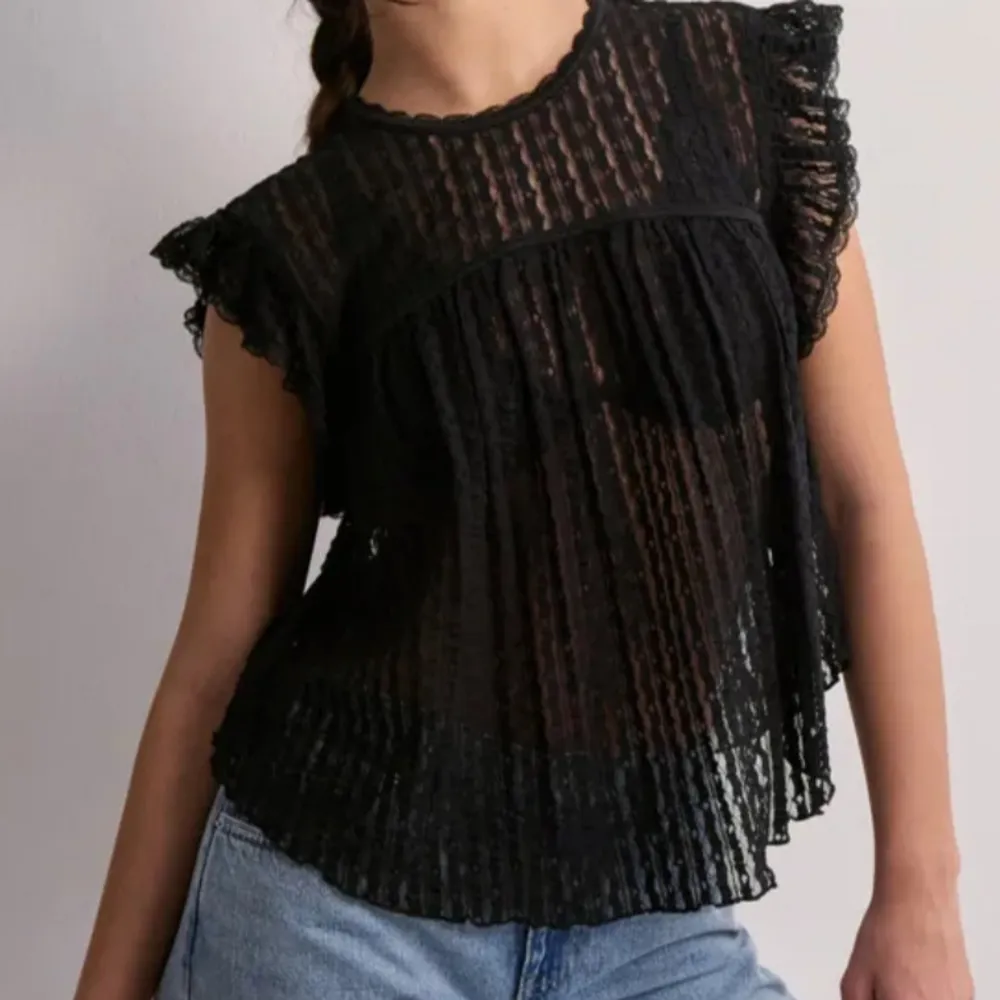 Säljer en elegant svart spetsblus från Nelly i storlek XS. Blusen har korta ärmar med volangdetaljer och ett knytband i nacken. Perfekt för en stilfull look. En jätte fin blus som bara inte kommit till användning. Använd 1 gång och sedan glömt att använda. Frakt tillkommer, alltså jag betalar inte frakten.. Puserot.