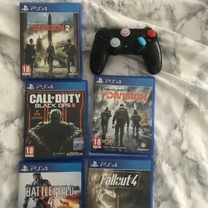 PS4-spel och handkontroll - Samling av PS4-spel inklusive 'The Division 2', 'Call of Duty: Black Ops III', 'Tom Clancy's The Division', 'Battlefield 4' och 'Fallout 4'. Inkluderar även en svart PS4-handkontroll med färgglada knappar. Perfekt för spelentusiaster som gillar action och äventyr.