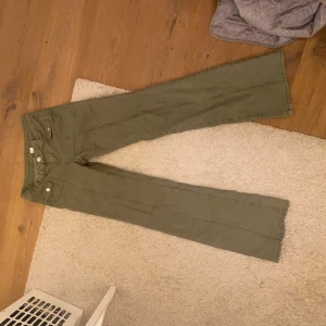 Gröna byxor med vida ben - Snygga gröna byxor med vida ben och låg midja. Perfekta för en avslappnad stil. Byxorna har knappar och dragkedja framtill.