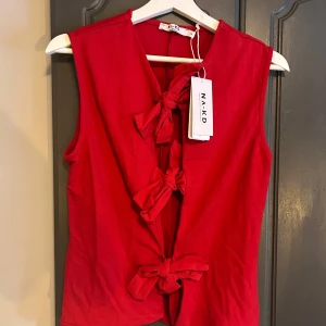Röd knyt topp från NA-KD - Snygg röd  topp från NA-KD med knytning framtill. Oanvänd, hann inte skicka tillbaka den bara… jättefin röd färg. Nypris 399kr. 