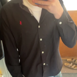 Svart skjorta från Polo Ralph Lauren - Säljer en svart Ralph lauren skjorta! Skjortan är storlek S/XS och är perfekt till alla tillfällen och jag säljer den då jag har storlek M. Skicket på skjortan är 9/10 då den använts någon gång. Nypris som ni kan se är 1300 men mitt pris endast 399!🥂                        Skriv vid minsta fråga eller fundering!💭