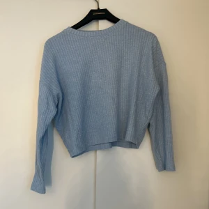 Ljusblå ribbad tröja från H&M - Säljer en ljusblå ribbad tröja från H&M. Tröjan har en croppad passform och långa ärmar, perfekt för en avslappnad stil. Den är mjuk och bekväm, idealisk för kyligare dagar.