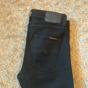 Svarta jeans från Nudie Jeans - Snygga svarta jeans från Nudie Jeans i modellen Lean Dean vilket är en slim passform. Tillverkade av 99% bomull och 1% elastan för en bekväm passform. Perfekta för en stilren look. Har lagats tidigare på nudie men utöver det i mycket bra skick. Strlk W 29 L32, sänker priset 50kr vid snabb och smidig affär💯