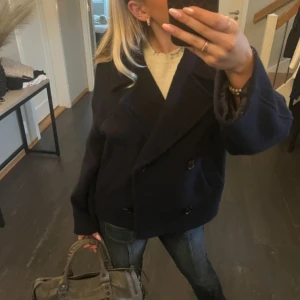 Mörkblå  kappa - Snygg mörkblå kappa med dubbelknäppning och bred krage. Perfekt för kyligare dagar och ger en stilren look. Passar bra till både jeans och klänning.
