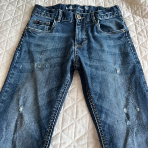 Blå jeans från LAB Industries - Snygga blå jeans från LAB Industries med slitna detaljer för en trendig look. Tillverkade av mer hållbart denim. Perfekta för en avslappnad stil.