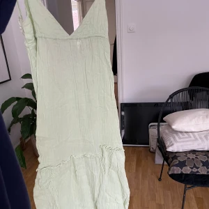 Ljusgrön långklänning med öppen rygg - Säljer en ljusgrön långklänning med smala justerbara axelband och öppen rygg med knytning. Perfekt för varma sommardagar.