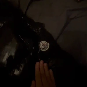 Svart  pufferjacka med huva - Snygg svart  pufferjacka med glansig yta och praktisk huva. Jackan har en dragkedja framtill och två fickor med dragkedjor. Perfekt för kyliga dagar.