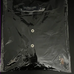 Svart skjorta från U.S. Polo Assn. - Snygg svart skjorta från U.S. Polo Assn. med klassisk design och knappar framtill. Perfekt för en stilren look.