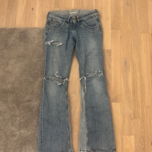 Blå jeans från Lee - Snygga lågmidjade  blå jeans från LEE. Utsydda till bootcut och klippta hål vid knäna och ena låret💕 W25 L31 