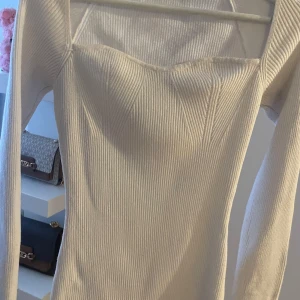 Vit ribbad långärmad topp - Snygg vit ribbad topp med långa ärmar och en elegant passform. Perfekt för en stilren look.