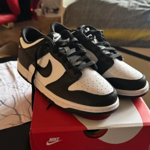 Nike Dunk i svart och vitt. Pris kan diskuteras  - Snygga Nike Dunk sneakers i klassisk svart och vit färgkombination. Skorna har en stilren design med snörning och den ikoniska Nike-loggan på sidan. Perfekta för en sportig och trendig look.