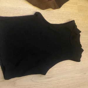 Svart ribbad topp - Säljer en stilren svart ribbad topp i storlek XS. Perfekt för lager-på-lager eller att bära som den är. Enkel och mångsidig design.