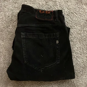 Svarta jeans från Dondup - Feta svarta byxor från Dondup. Perfekta för en stilren look med en smal passform. Byxorna har en klassisk design med fickor och knappdetaljer.