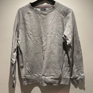 Grå sweatshirt från Lindbergh - Säljer en stilren grå sweatshirt från Lindbergh. Tröjan har en klassisk rund hals och långa ärmar, perfekt för en avslappnad look. Den är tillverkad i ett mjukt material som ger en bekväm passform.