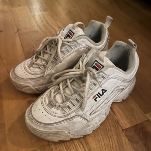 Vita sneakers från Fila - Säljer ett par vita Fila sneakers i helt okej skick. De är slitna men inget överdrivet:) Perfekta för en casual look och passar till det mesta. Storlek dam 37. Lite smutsiga men kan enkelt rengöras för att se fräscha ut igen.
