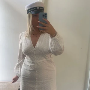 Vit klänning  - Säljer en superfin vit spetsklänning med v-ringning och långa ärmar. Perfekt för studenten eller sommarens fester! Klänningen har en figurnära passforml. Den är både elegant och bekväm.