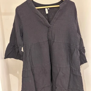 Mörkgrå klänning från Only  - Säljer en stilren mörkgrå klänning från only storlek XS. Klänningen har en v-ringad design och trekvartsärmar, perfekt för både vardag och fest. Materialet är mjukt och bekvämt.