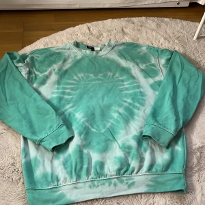 Turkos tie-dye sweatshirt - Säljer en cool turkos tie-dye sweatshirt i bra skick använd en gång. Den har en avslappnad passform och är perfekt för både vår och sommar. Tröjan är långärmad och gjord av mjukt material, vilket gör den superbekväm att ha på sig. Perfekt för chill dagar eller när du vill ha en färgklick i garderoben!