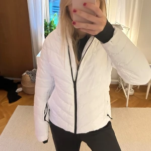 Vit skid-pufferjacka från McKinley - Säljer en snygg vit pufferjacka, använd som skidjacka, från McKinley i storlek 38. Jackan har en dragkedja framtill och en mysig huva. Jackan har även snöskydd i och är endast använd i en vecka.