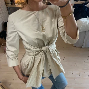 Beige blus med knytband - Snygg beige blus med trekvartsärm och ett knytband i midjan. Perfekt för en stilren look. SUPER fin!❤️❤️passar alla pga man kan skystera!