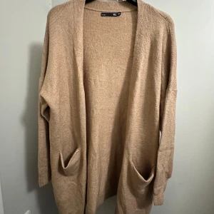 Beige kofta  - Mysig beige kofta från Lager 157 i storlek M/L som är oanvänd. Perfekt för kyliga dagar med sina långa ärmar och praktiska fickor framtill och mysig material. 