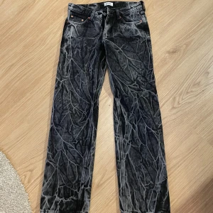 Svarta jeans från Weekday - Snygga svarta jeans från Weekday med en cool acid wash-effekt. De har en rak passform och låg midja, vilket ger en avslappnad stil. 